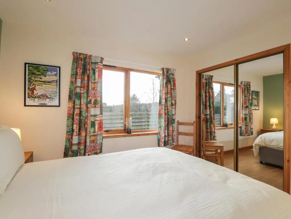 a bedroom with a white bed and a window at Bruach Gorm Cottage in Grantown on Spey