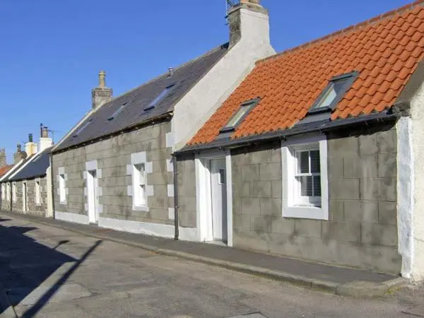 a row of buildings with white doors and a red roof at 85 Seatown in Cullen