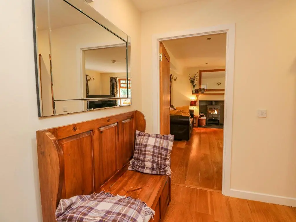 a living room with a bench and a mirror at Thistle Dhu in Newtonmore