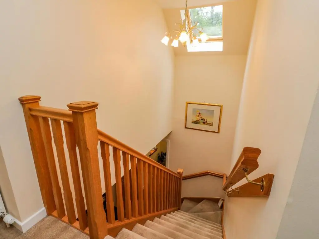 a staircase in a home with a chandelier at Thistle Dhu in Newtonmore