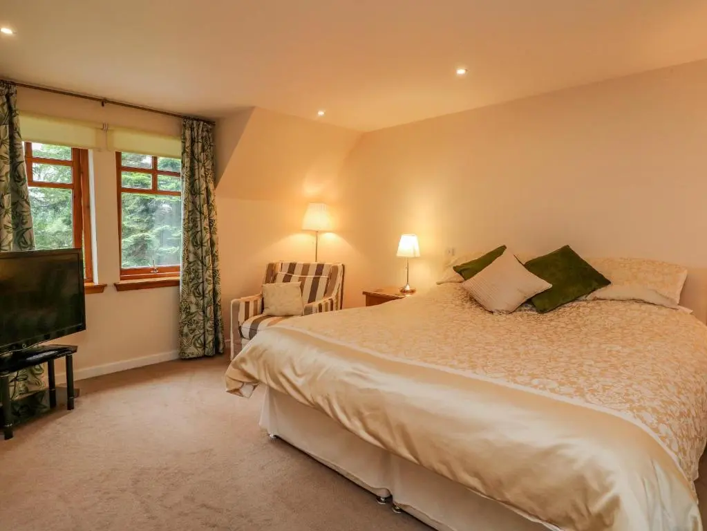 a bedroom with a bed and a flat screen tv at Thistle Dhu in Newtonmore