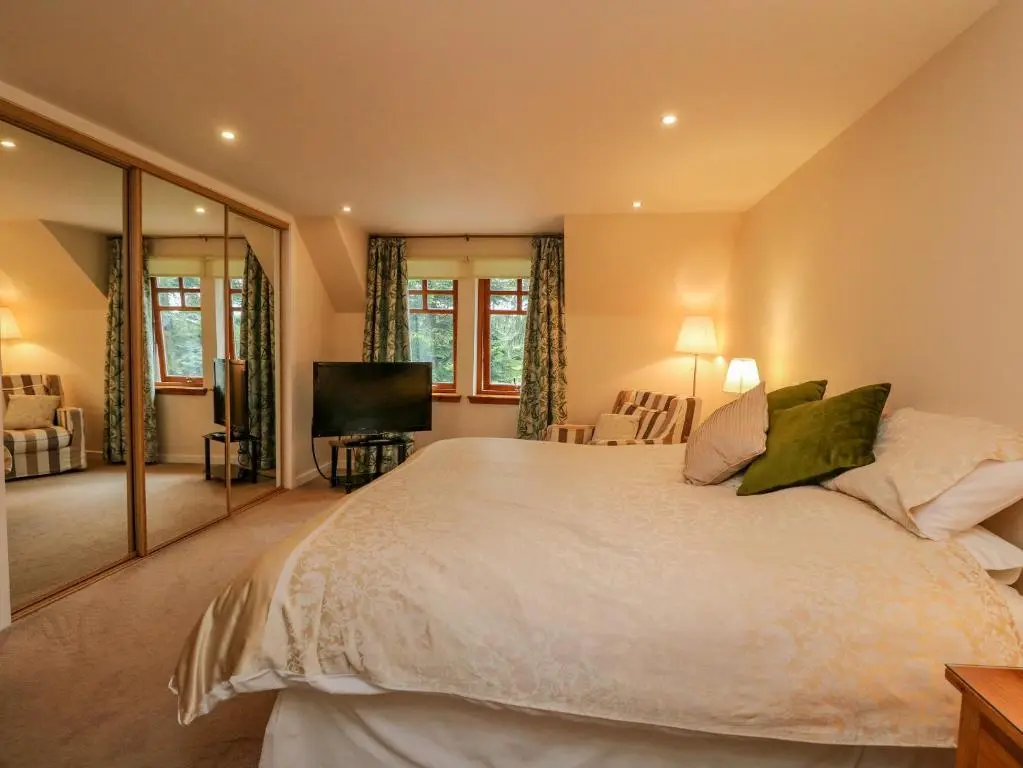 a bedroom with a large white bed and a television at Thistle Dhu in Newtonmore
