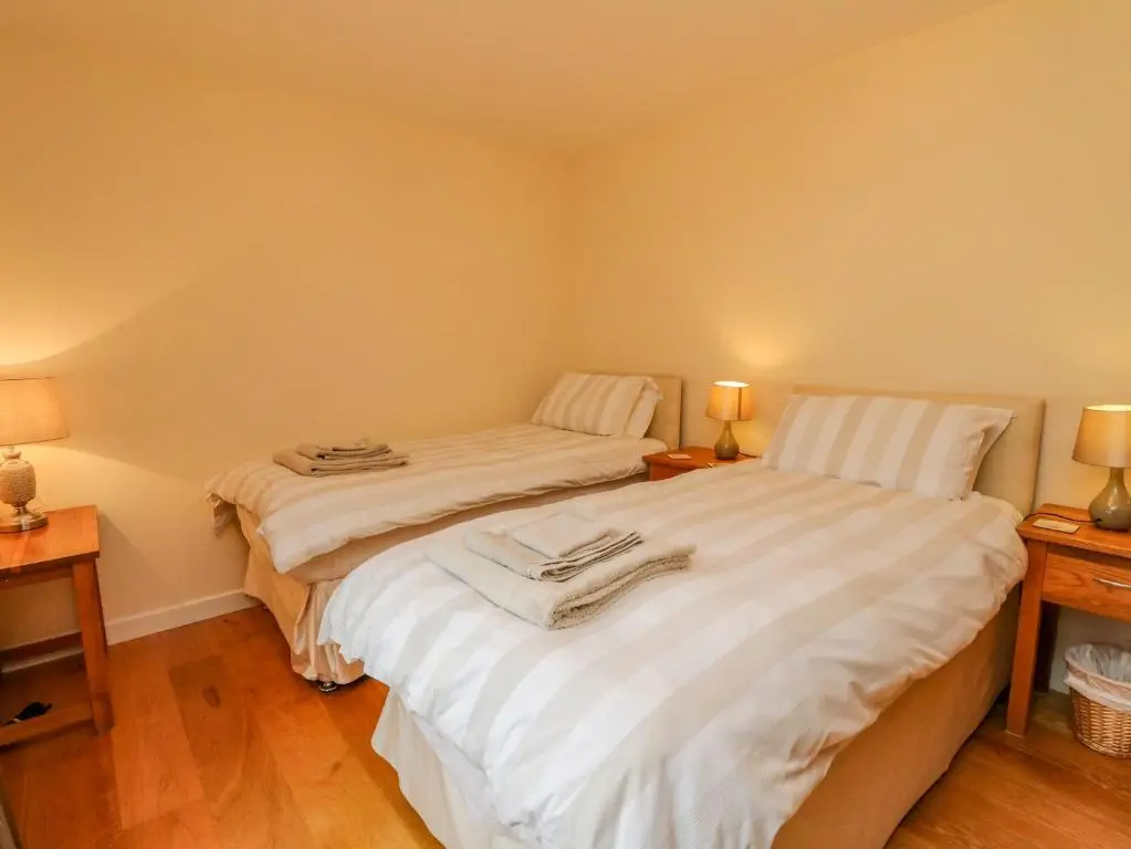 two twin beds in a room with two lamps at Thistle Dhu in Newtonmore