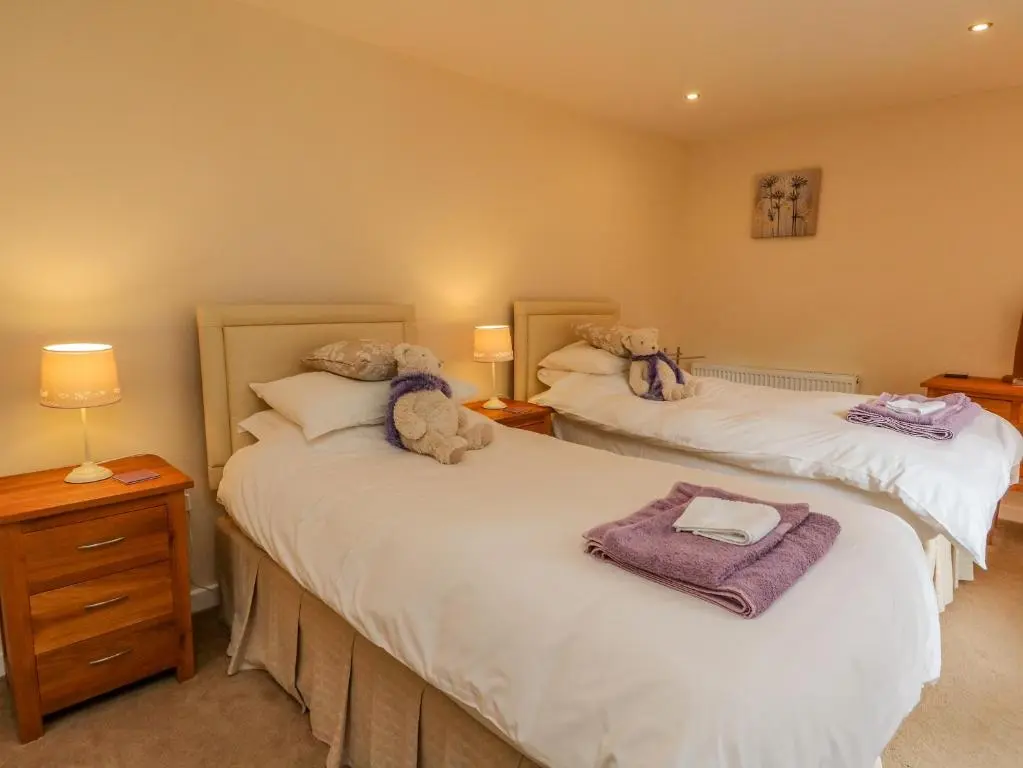 two beds with stuffed animals on them in a bedroom at Thistle Dhu in Newtonmore