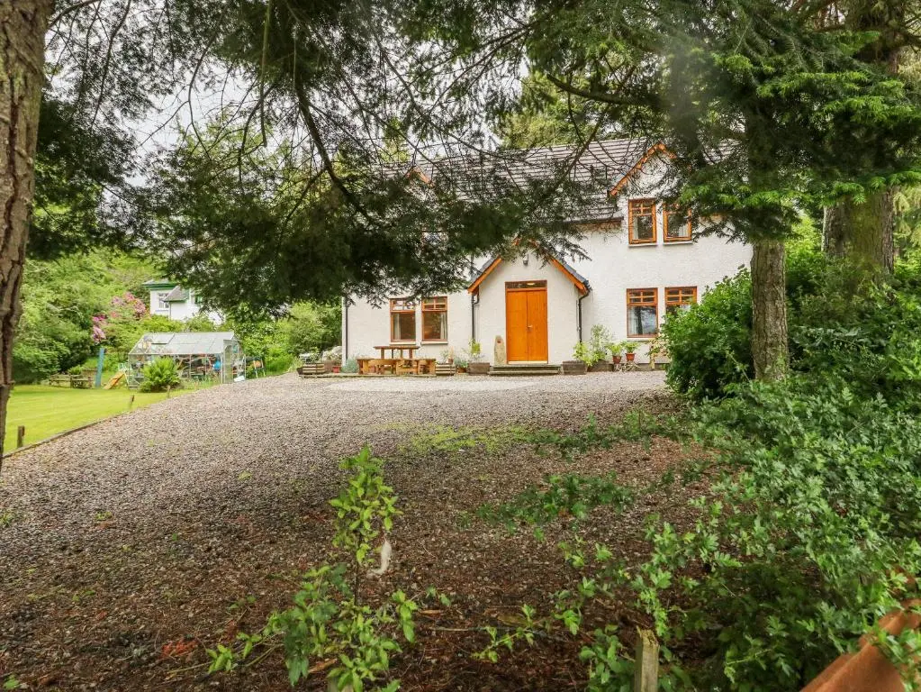 a white house with an orange door on a driveway at Thistle Dhu in Newtonmore