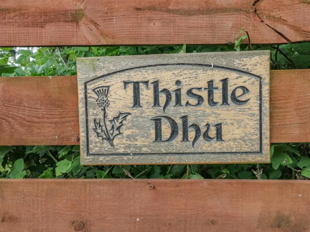 a sign on a wooden fence with the words thrisel dip at Thistle Dhu in Newtonmore