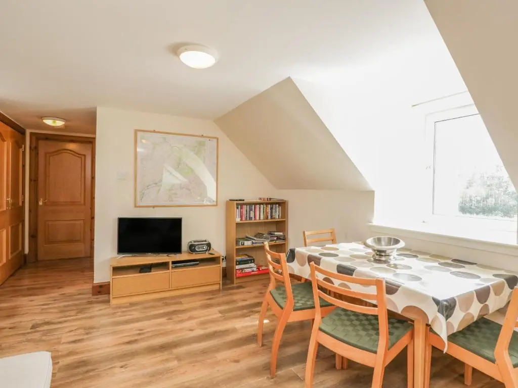 a dining room with a table and chairs and a tv at 10 Monarch Country Apartments in Newtonmore