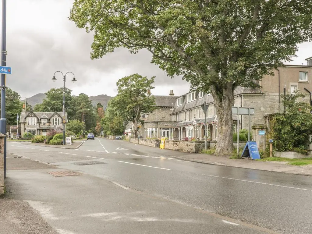 an empty street in a town with houses and a tree at 10 Monarch Country Apartments in Newtonmore