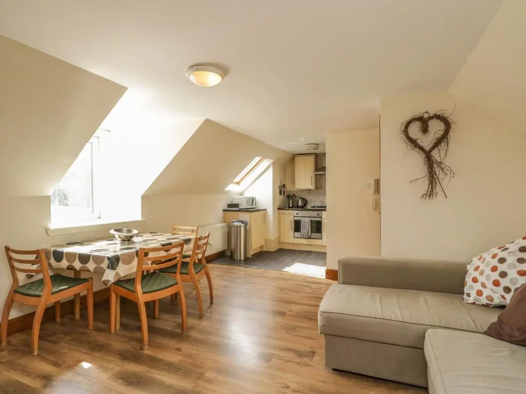 a kitchen and living room with a table and chairs at 10 Monarch Country Apartments in Newtonmore