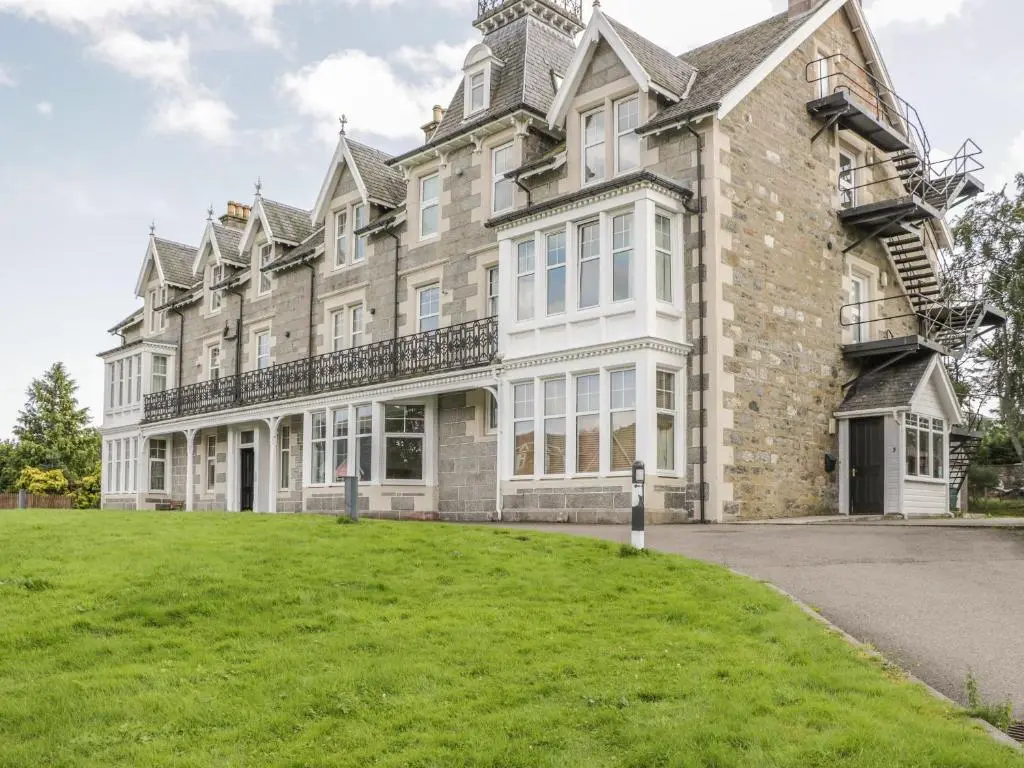 a large house with a grassy yard in front of it at 10 Monarch Country Apartments in Newtonmore