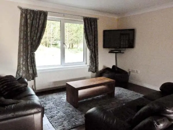 a living room with a couch and a table and a window at Braewood in Invermoriston