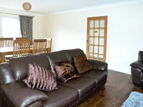 a black leather couch with pillows in a living room at Braewood in Invermoriston