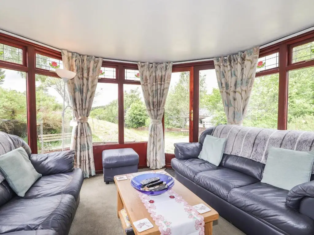 a living room with couches and a table at Blairgorm Croft in Nethy Bridge