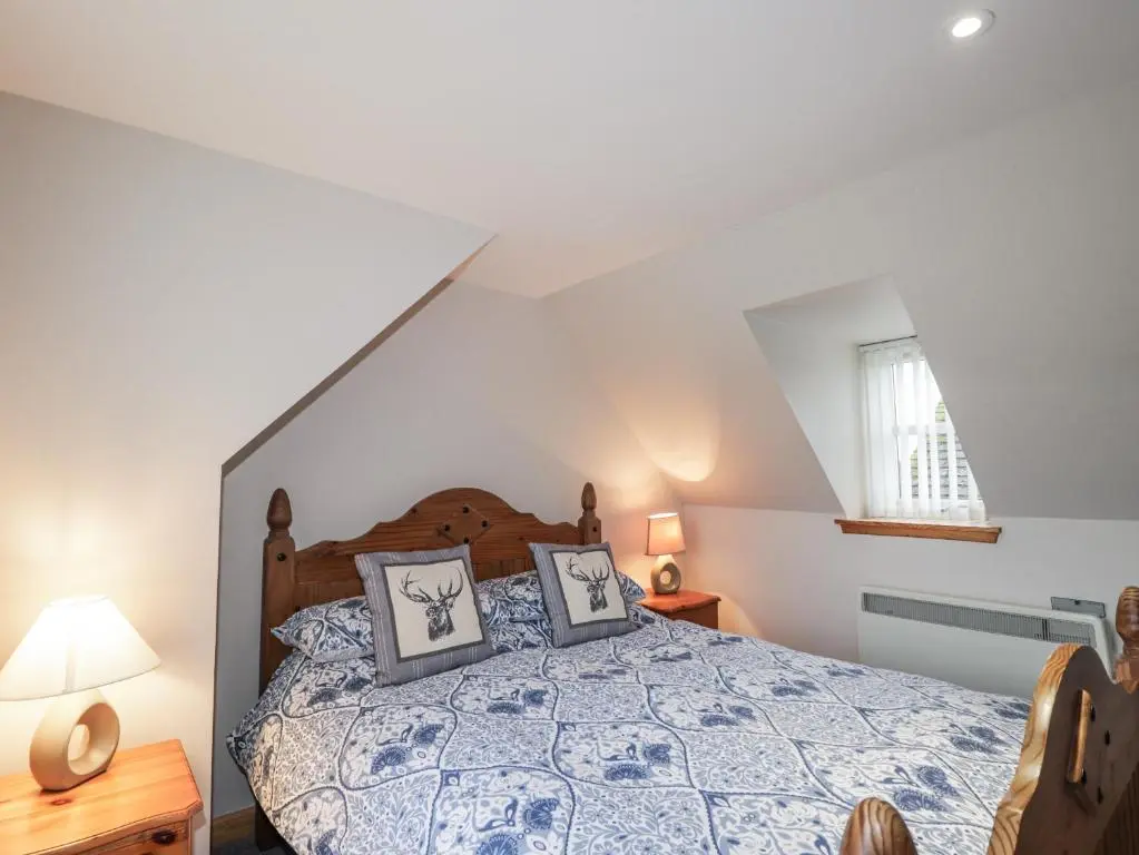 a bedroom with a bed with a blue comforter at The Croft House in Muir of Ord