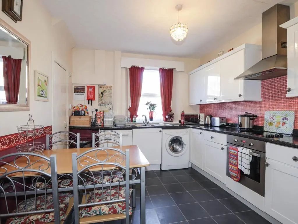 a kitchen with white appliances and a table and chairs at Holly Hoose in Findochty