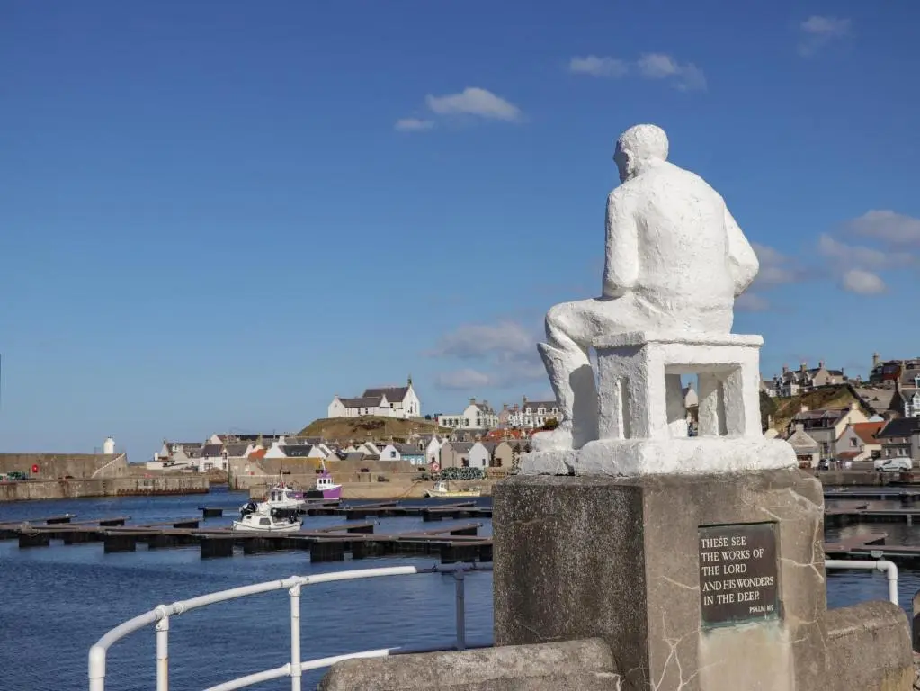 a statue of a man sitting on a pier at Holly Hoose in Findochty