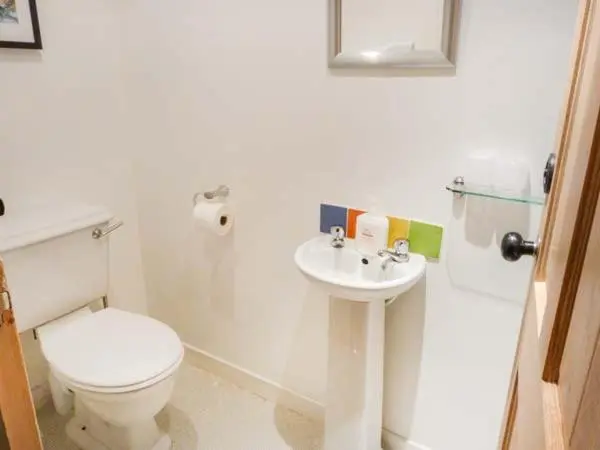 a white bathroom with a toilet and a sink at Easter Duthil Cottage in Duthil