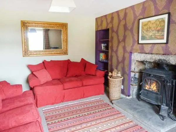 a living room with a red couch and a fireplace at Easter Duthil Cottage in Duthil