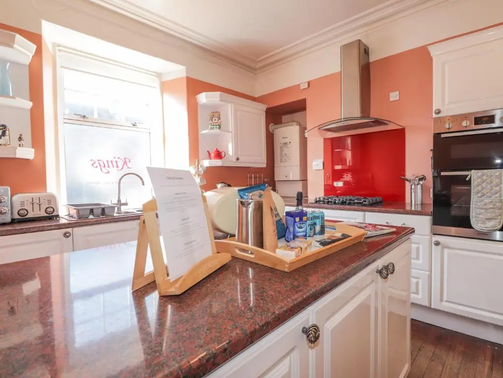 a kitchen with orange walls and a counter top at 1 Seafield Street in Cullen