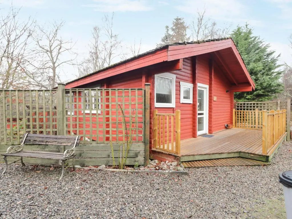 a red tiny house with a wooden deck at Spruce Lodge in Strathpeffer