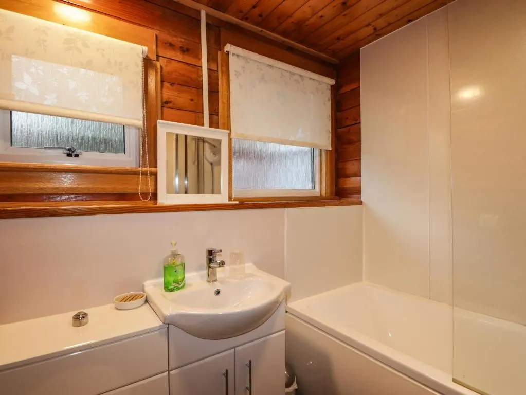 a bathroom with a sink and a tub at Spruce Lodge in Strathpeffer