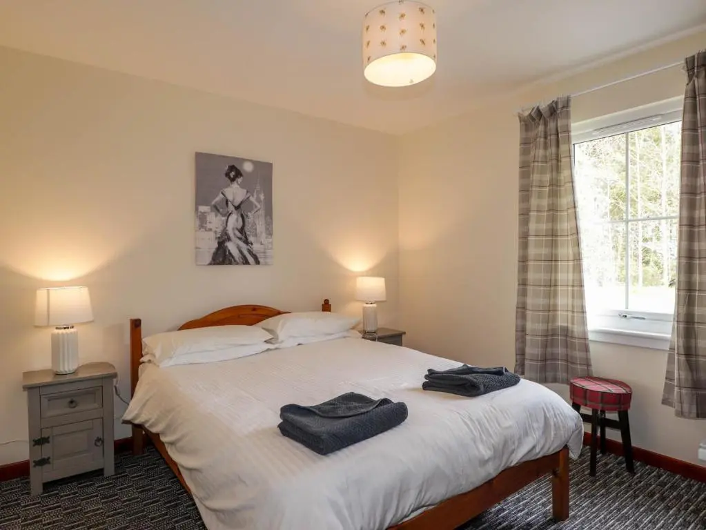 a bedroom with a bed with two towels on it at Stone Water Cottage in Contin