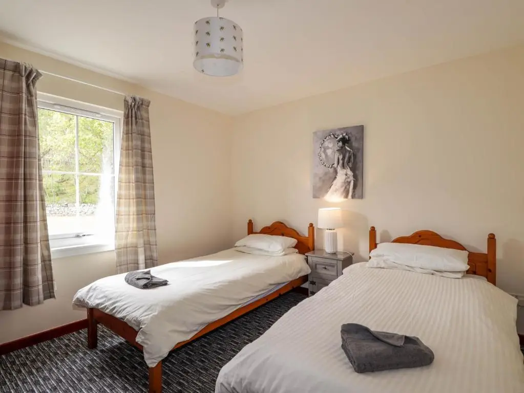 two twin beds in a room with a window at Stone Water Cottage in Contin