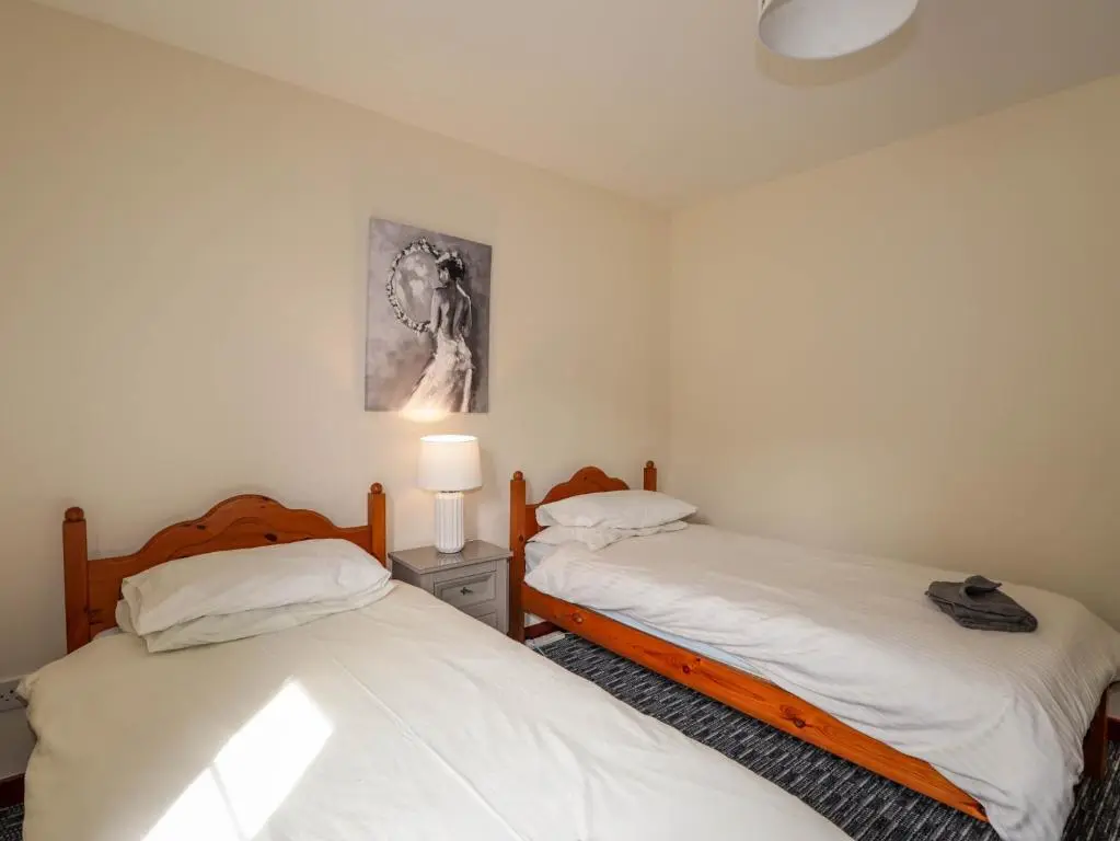 two beds in a room with white walls at Stone Water Cottage in Contin