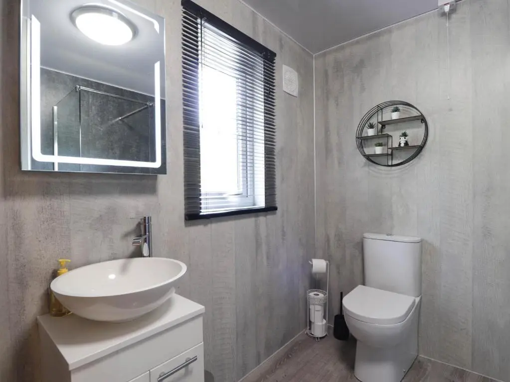 a bathroom with a sink and a toilet and a window at Stone Water Cottage in Contin
