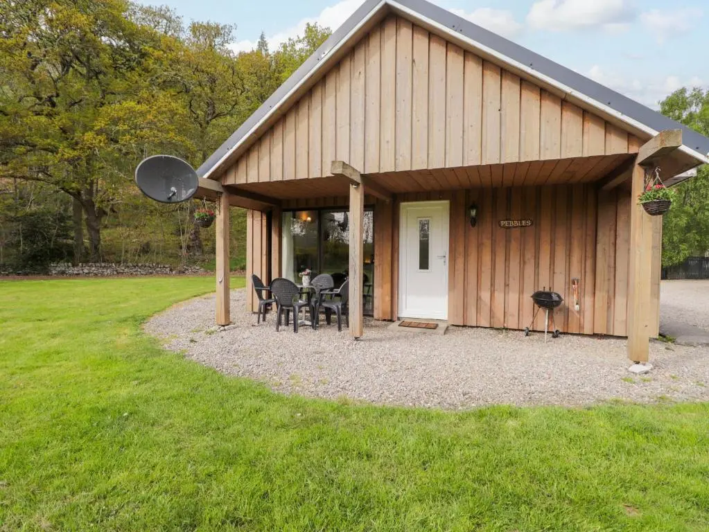 a barn with a table and chairs in a yard at Pebbles Cottage in Contin