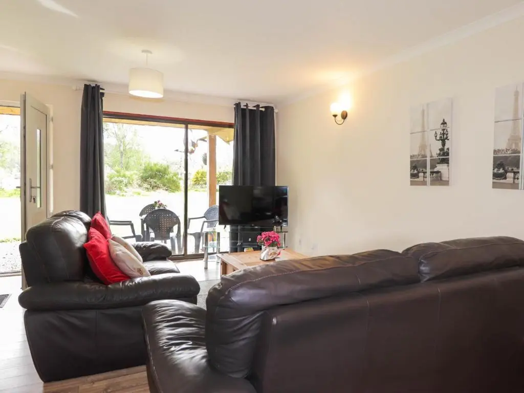 a living room with two leather couches and a television at Pebbles Cottage in Contin
