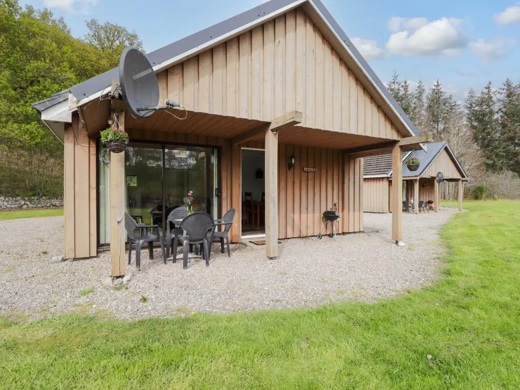 a barn with a table and chairs in front of it at Pebbles Cottage in Contin