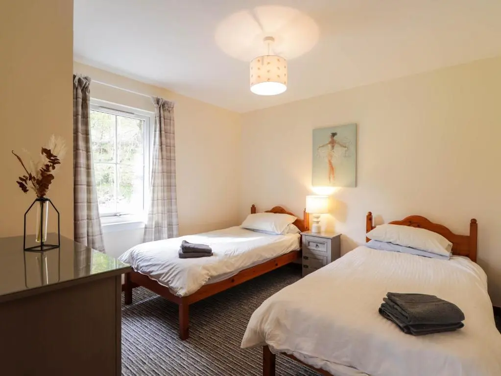 two beds in a room with a window at Pebbles Cottage in Contin