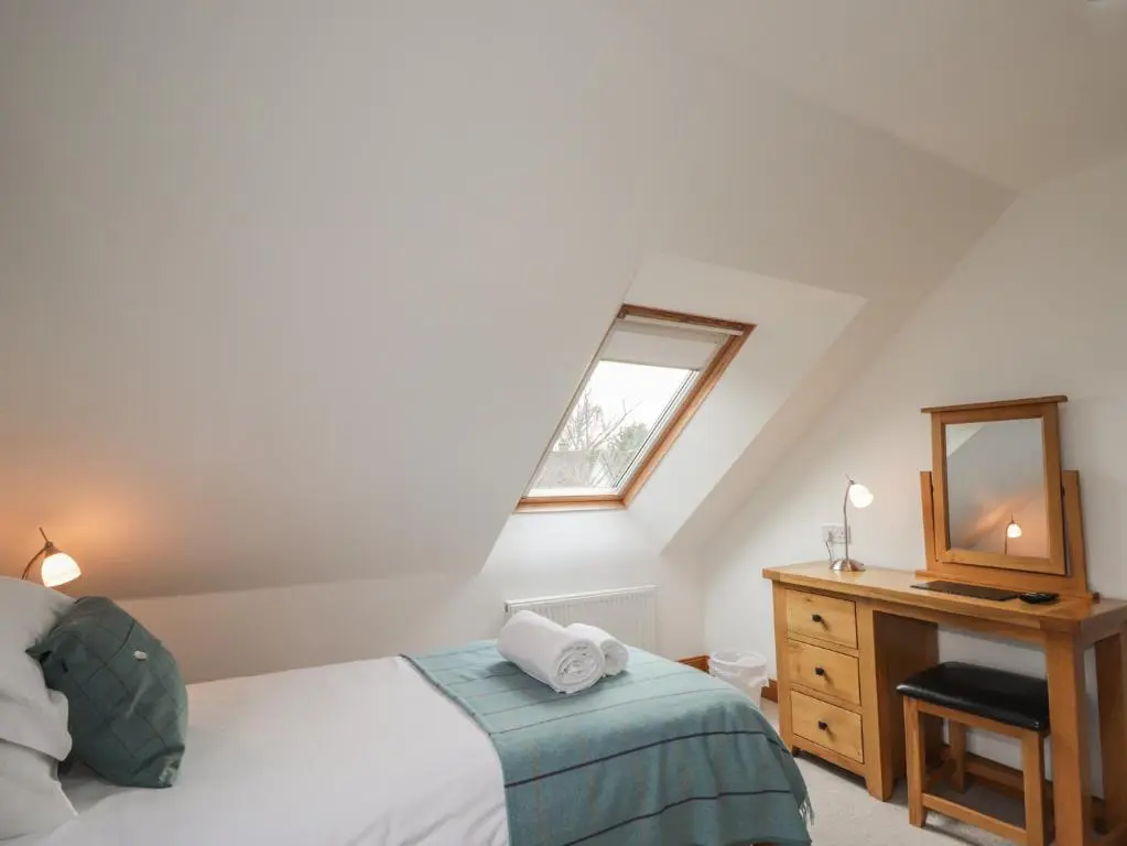 a bedroom with a bed and a dresser and a mirror at Little Chestnut in Muir of Ord