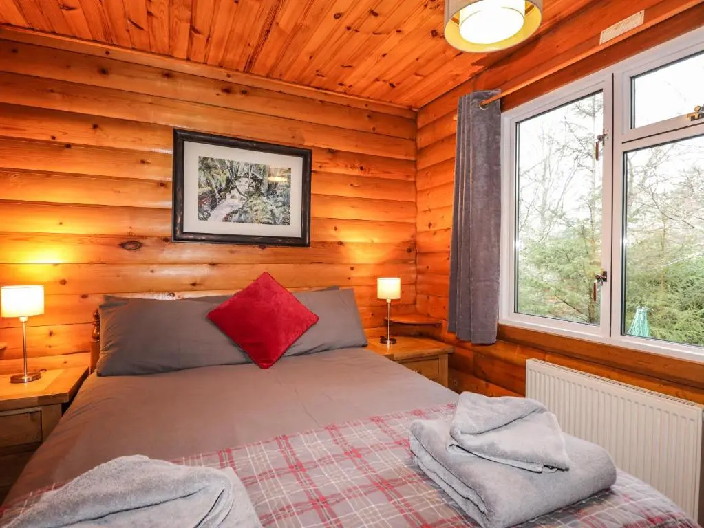 a bedroom with a bed in a wooden cabin at Rowan Lodge in Strathpeffer