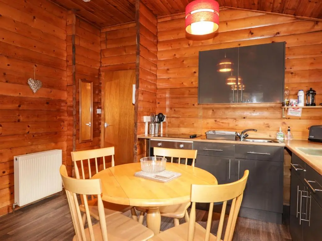 a kitchen and dining room with a table and chairs at Rowan Lodge in Strathpeffer