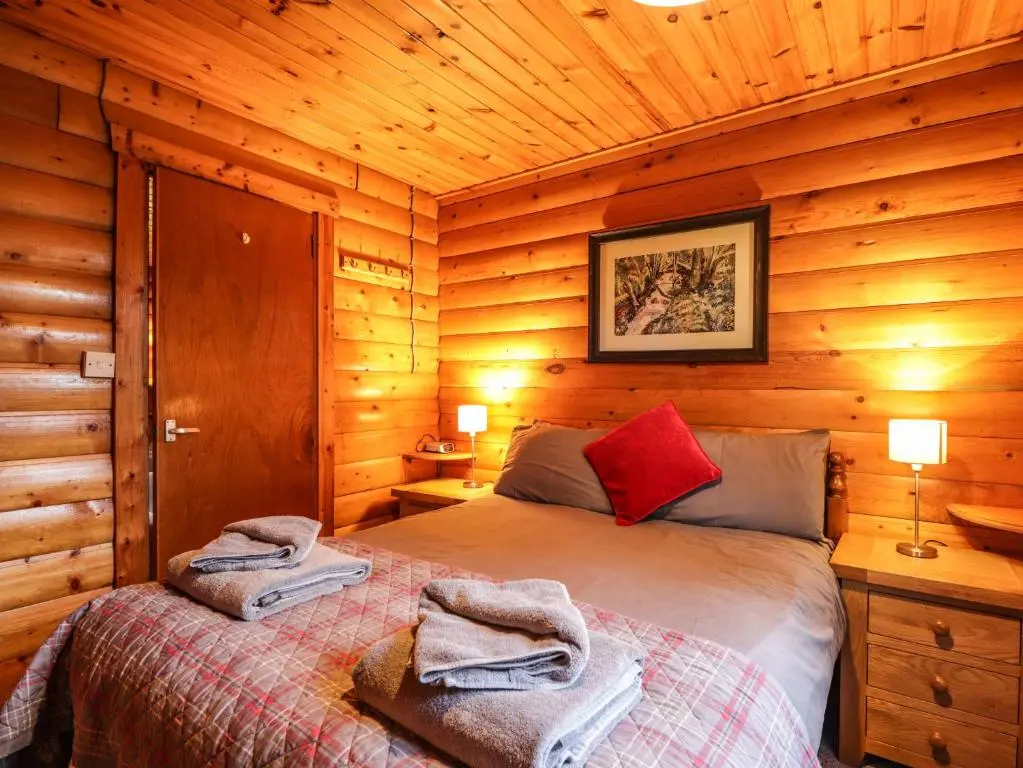 a bedroom with a bed in a wooden cabin at Rowan Lodge in Strathpeffer