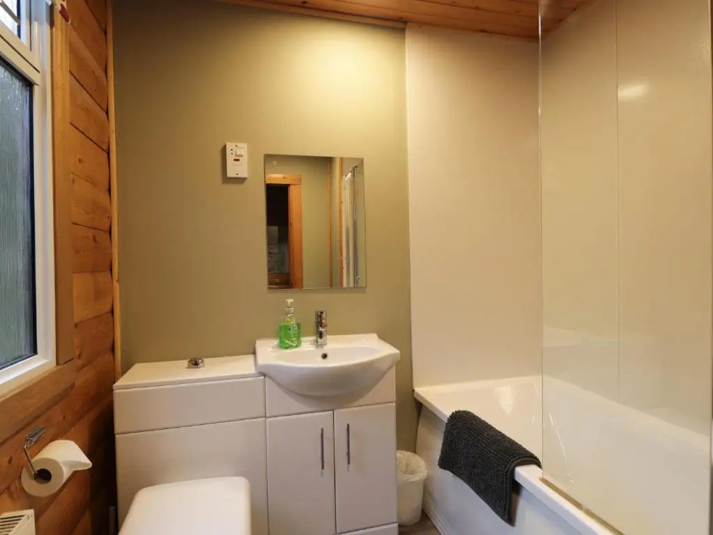 a bathroom with a sink and a toilet and a tub at Rowan Lodge in Strathpeffer