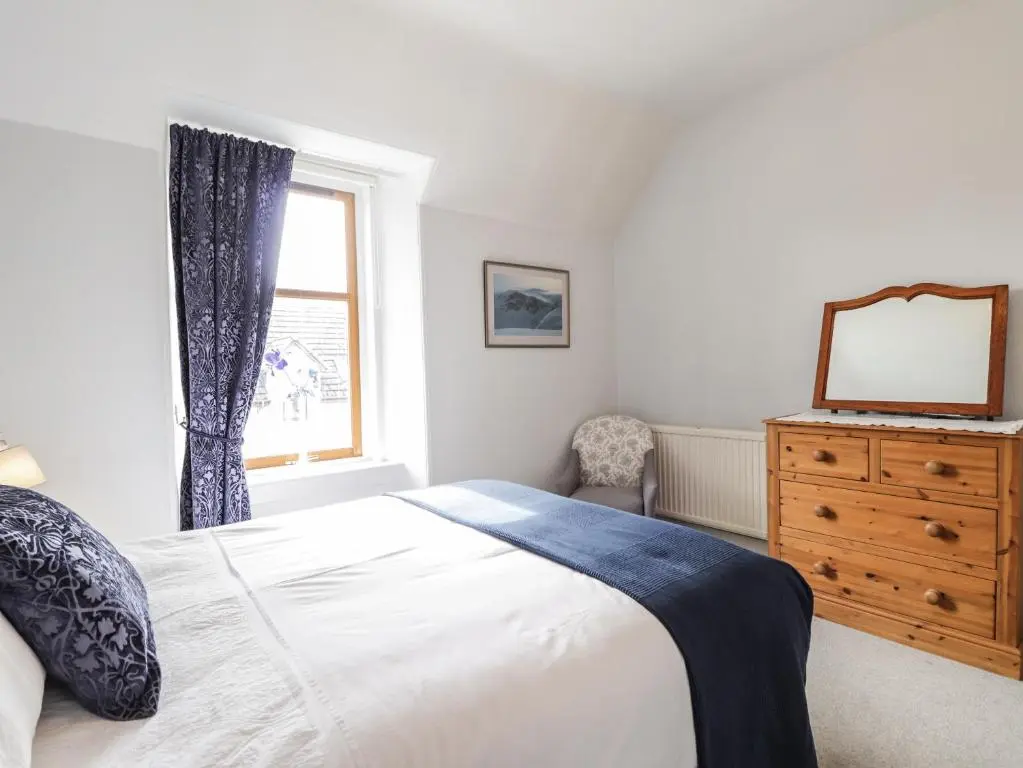 a bedroom with a bed and a dresser and a window at Aultmore in Kingussie