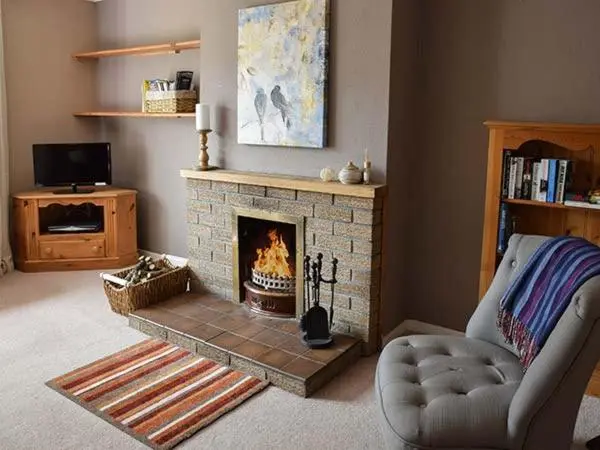 a living room with a fireplace and a chair at Cottage Fia in Jamestown