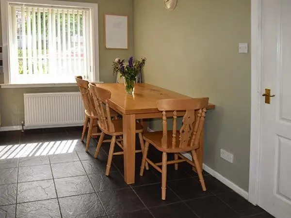 a dining room table with chairs and a vase of flowers at Cottage Fia in Jamestown