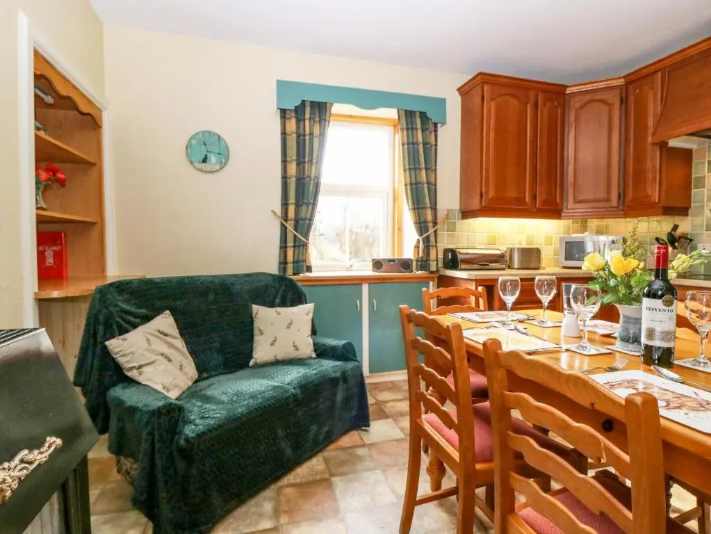 a kitchen with a table and a green couch at The West Wing in Skye of Curr