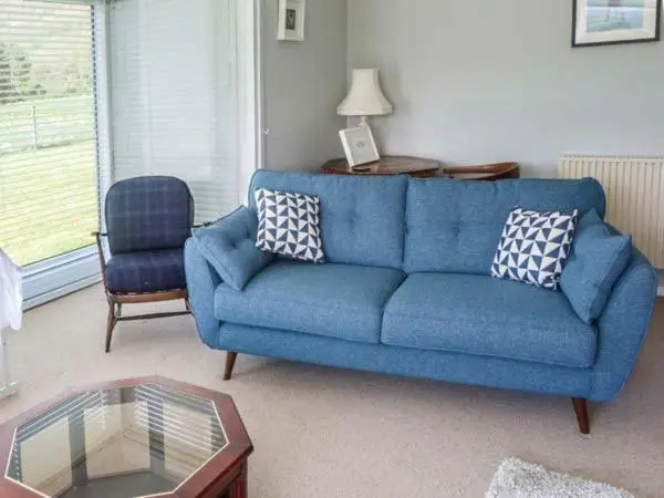 a blue couch and a chair in a living room at Fronthill in Newtonmore