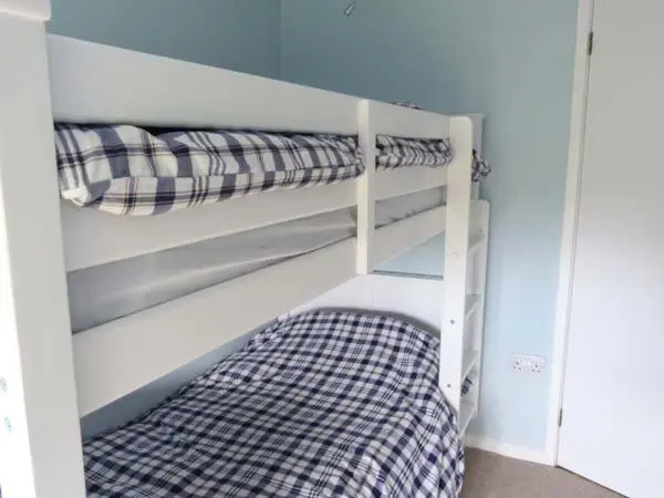 a white bunk bed with a checkered blanket on it at Fronthill in Newtonmore