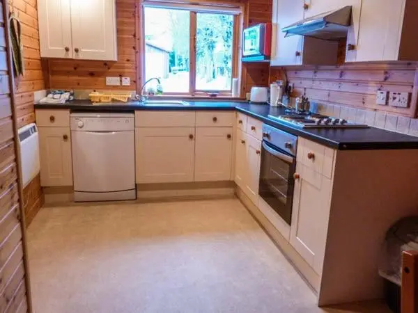 a kitchen with white appliances and a black counter top at Strathavon Chalet in Aviemore