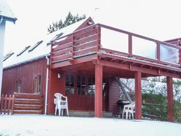 a cabin with two white chairs and a balcony at Strathavon Chalet in Aviemore