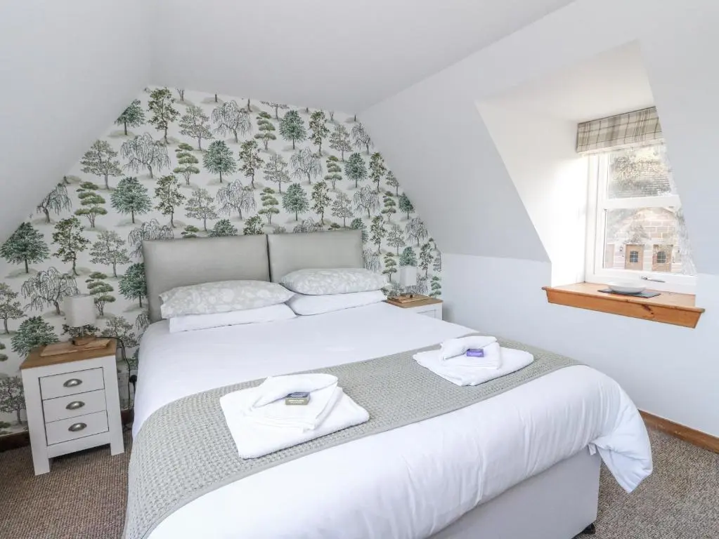 a bedroom with a white bed with towels on it at Deskford Cottage in Balblair