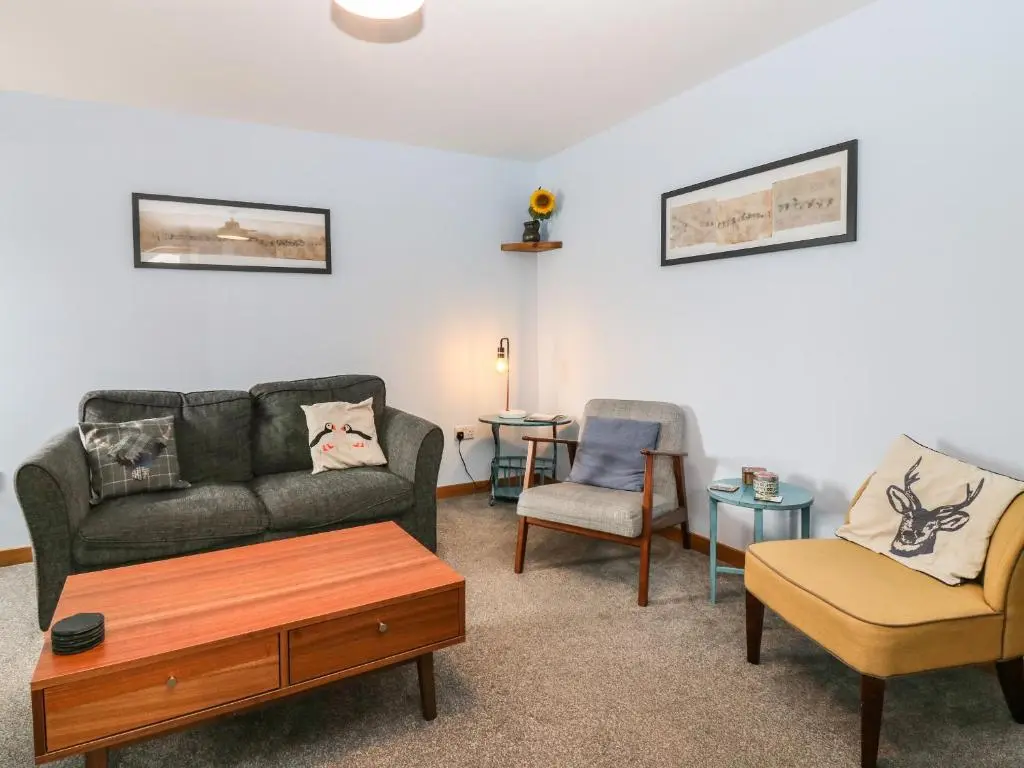 a living room with a couch and two chairs at 49 Crovie Village in Gardenstown