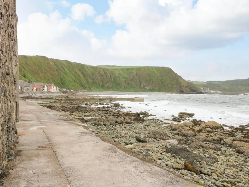 a dirt road next to a beach with the ocean at 49 Crovie Village in Gardenstown