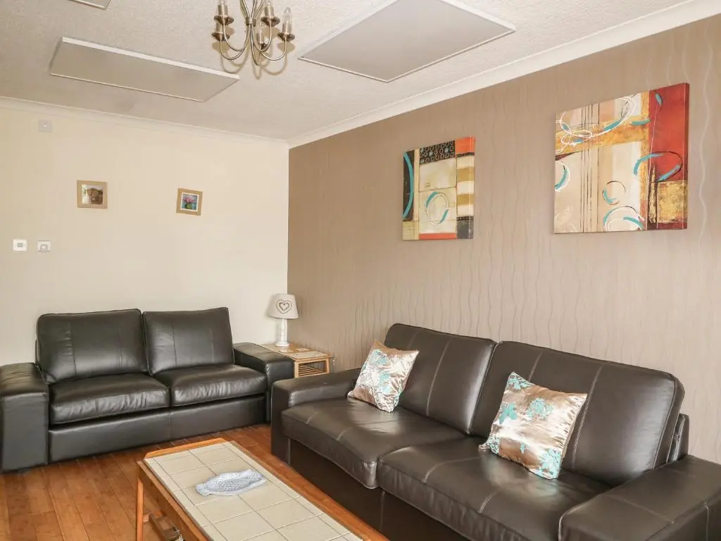 a living room with two leather couches and a table at 79 Corrour Road in Aviemore
